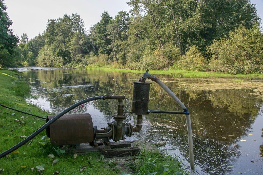 Pompe industriale de mare capacitate cu furtunuri care duc la apa unui râu cu nivel scăzut