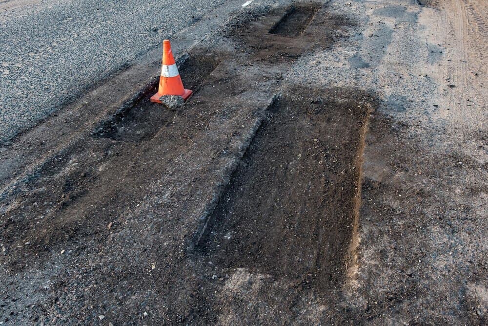 Drum asfaltat aflat în reparație, cu utilaje de asfaltare pe carosabil