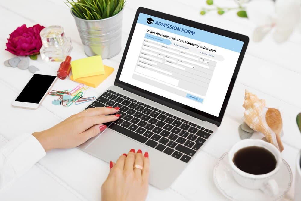 Laptop cu un formular online de aplicare deschis pe ecran, pe un birou cu documente