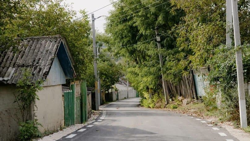 Stradă asfaltată de curând într-un sat din Moldova, cu case și copaci de-o parte și de alta