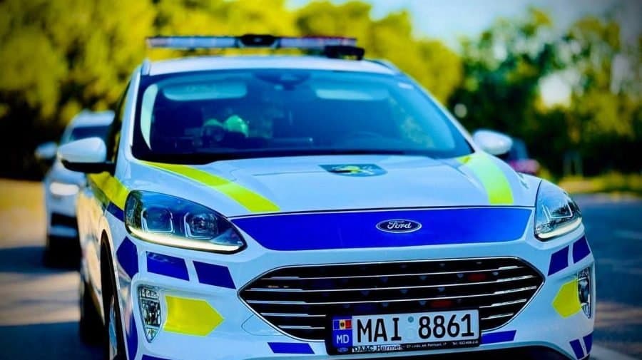 Mână care ține un telefon mobil lângă volanul unui automobil aflat în mers