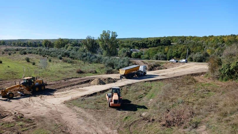 Pod rutier din beton în reparație peste un râu, cu utilaje de construcție pe șantier