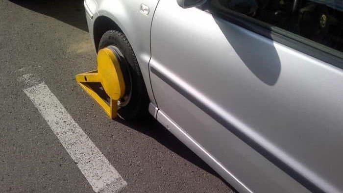 Automobil parcat pe o stradă din oraș, cu un dispozitiv de blocare montat pe roată