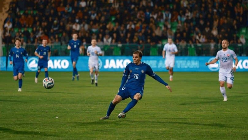 Minge de fotbal pe gazonul unui stadion, lângă poartă