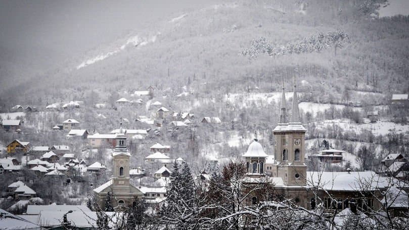 Stradă udă de ploaie într-un oraș european iarna, cu zăpadă topită pe margini