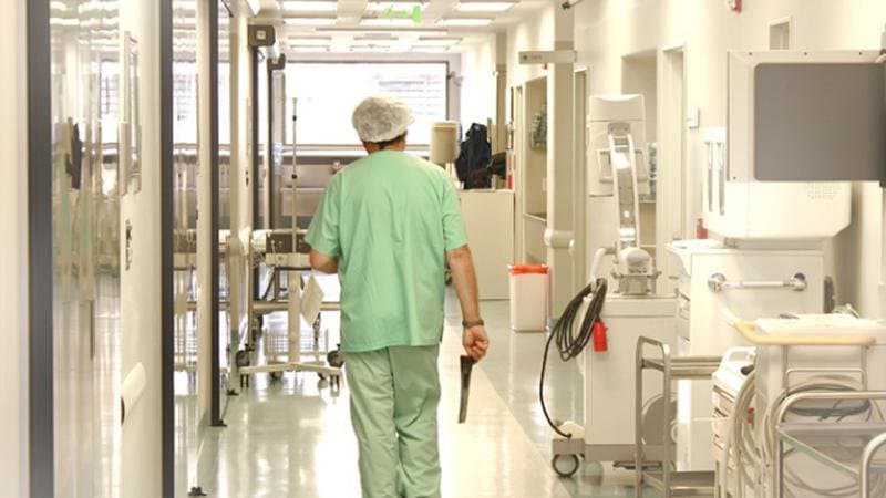 Clădire de spital raional, cu intrarea pentru pacienți și o ambulanță parcată în față