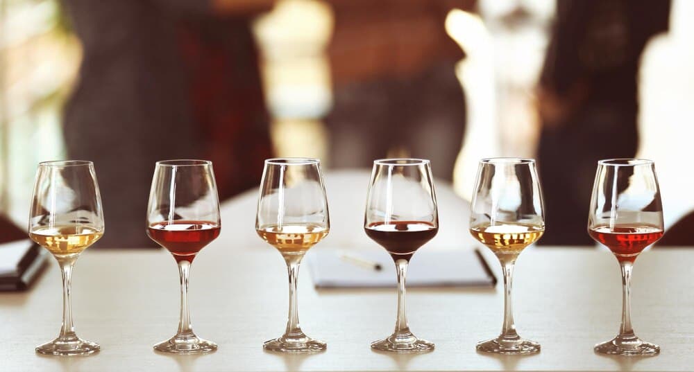 Pahare cu vin roșu și alb pe o masă de degustare, în aer liber