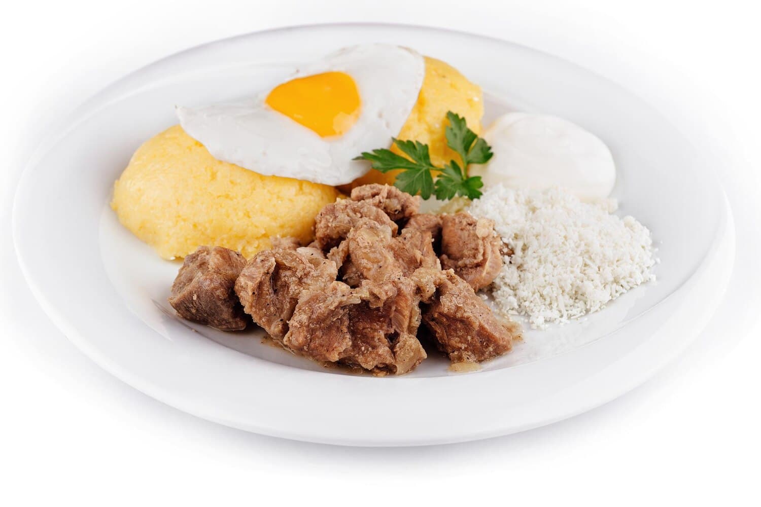 Bucăți de carne de porc înăbușită cu ceapă, două felii de mămăligă cu un ou ochi deasupra, brânză sfărâmată, smântână și o crenguță de pătrunjel pe o farfurie albă